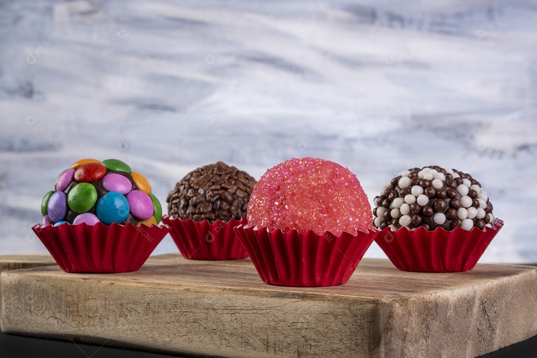 Brigadeiros variados na placa de madeira com fundo multicolorido