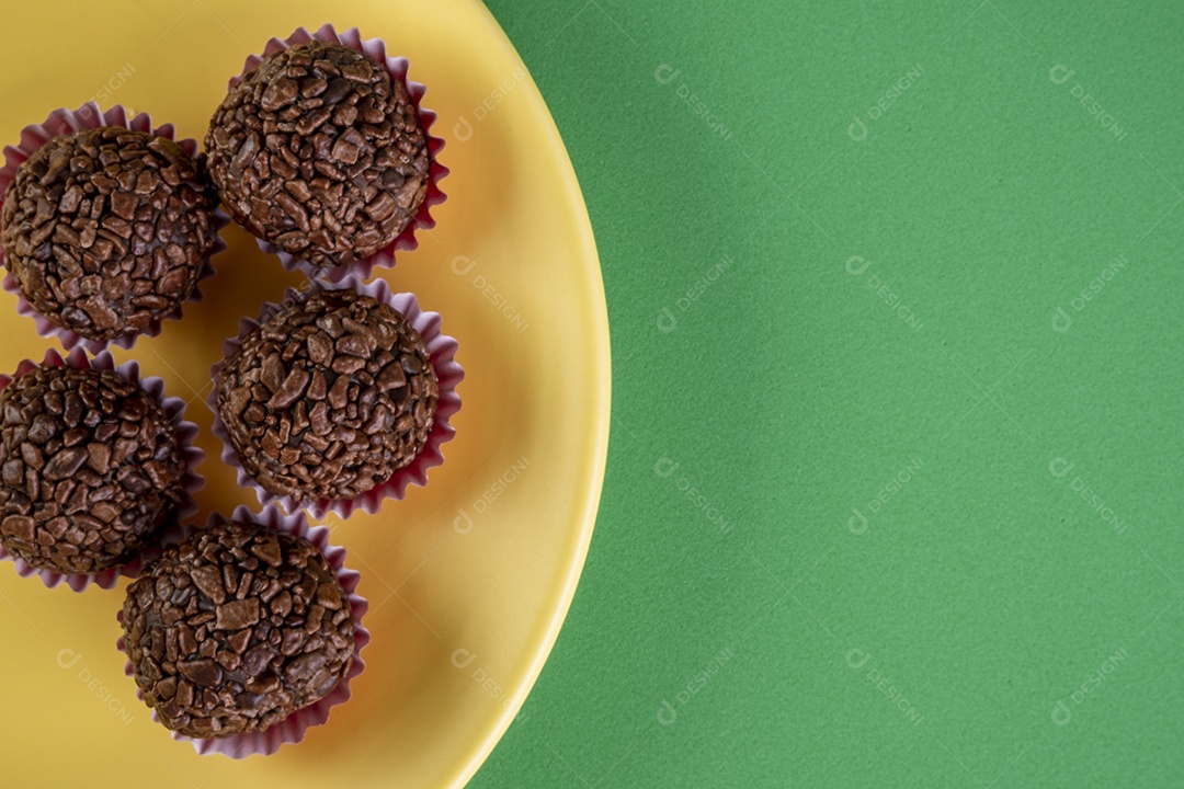 Brigadeiros em prato amarelo sobre fundo verde