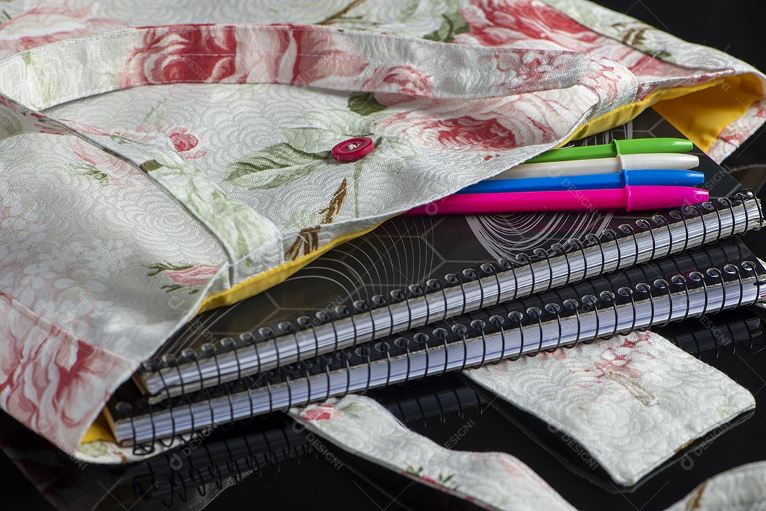 Bolsa de tecido com cadernos e canetas coloridas