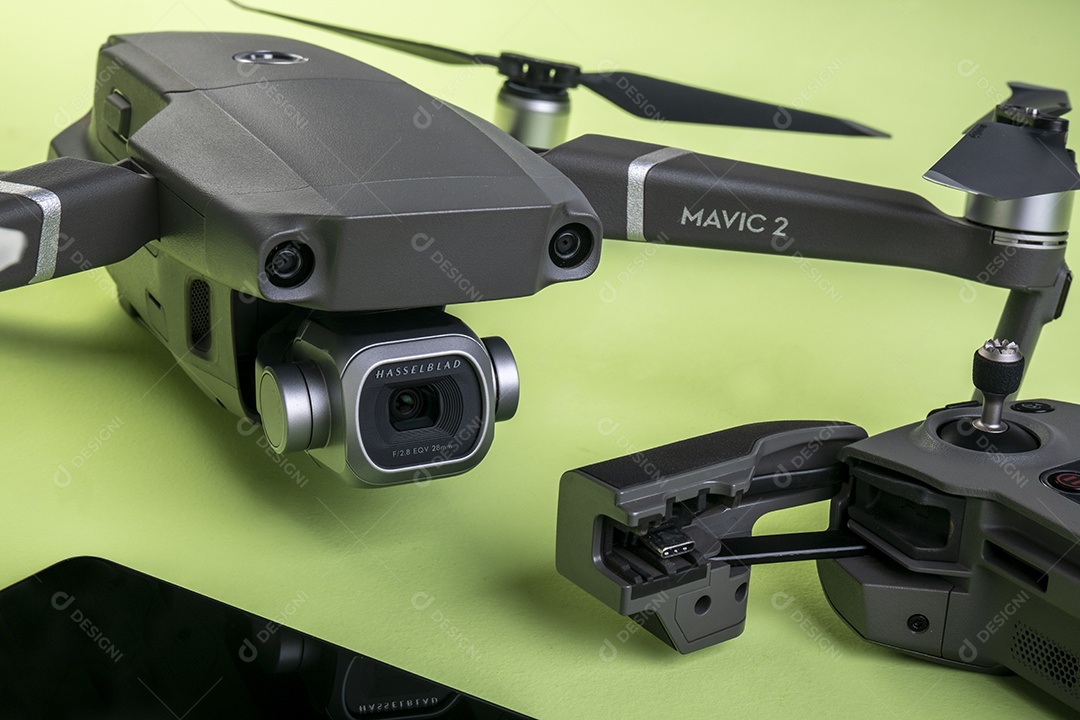 Drone DJI mavic 2 pro, seu controlador e um smartphone em fundo marrom.
