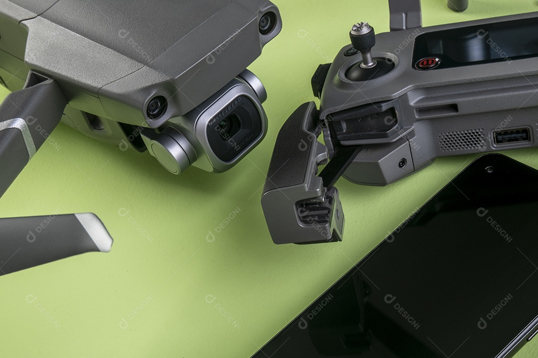 Drone DJI mavic 2 pro, seu controlador e um smartphone em fundo marrom.