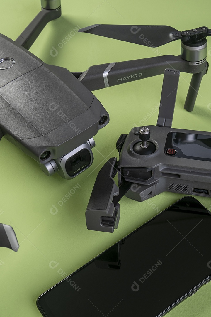Drone DJI mavic 2 pro, seu controlador e um smartphone em fundo marrom.