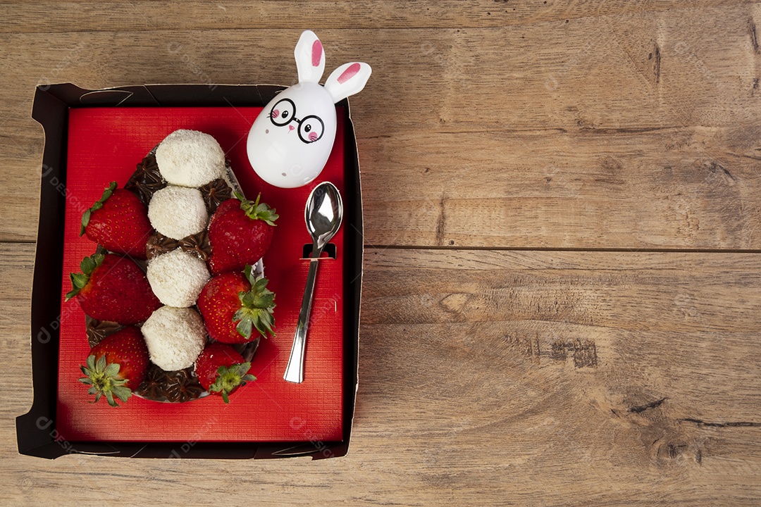 Caixa vermelha com meio ovo de páscoa, chocolates e morangos