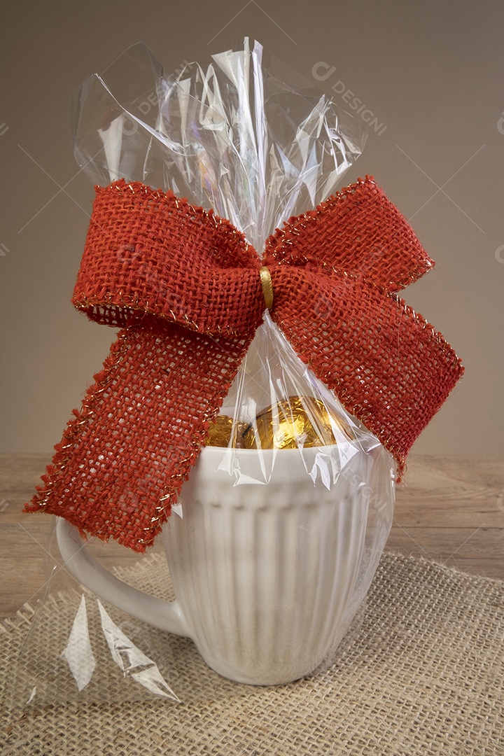 Caneca cheia de trufas de chocolate e decorada com um laço vermelho.