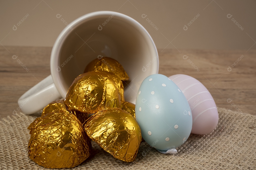 Trufas de chocolate embrulhadas em papel dourado ao lado de enfeites de Páscoa.