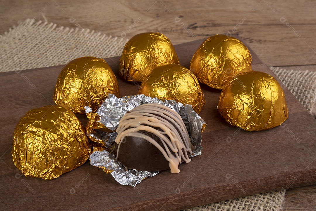 Trufas de chocolate embrulhadas em papel laminado em corte de madeira