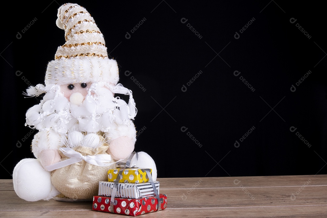 Boneca Papai Noel ao lado de caixas de presente