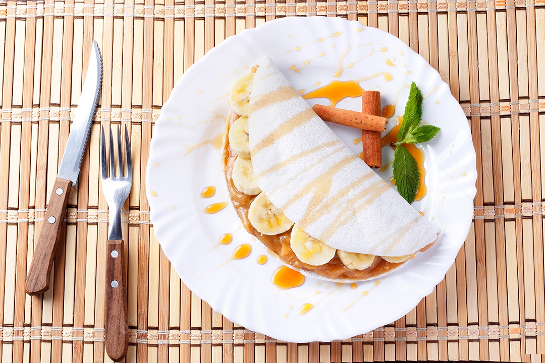 tapioca caseira ou beiju recheado com banana e leite condensado ou caramelo maltado na mesa de madeira rústica. vista do topo