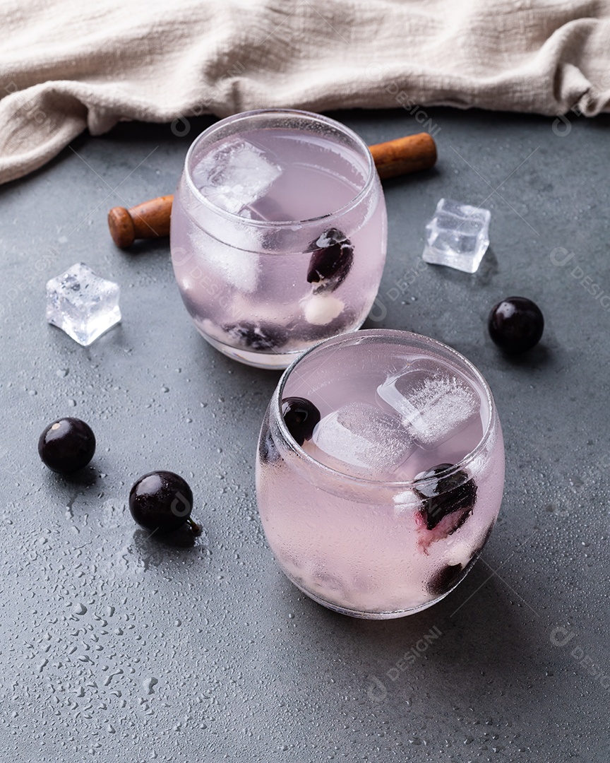Caipirinha de jabuticaba brasileira em copos com gelo e frutas sobre fundo de pedra.