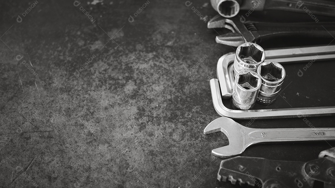 Ferramentas manuais consistindo de chaves, alicates, chaves de soquete, dispostas em fundo de chapa de aço antigo.