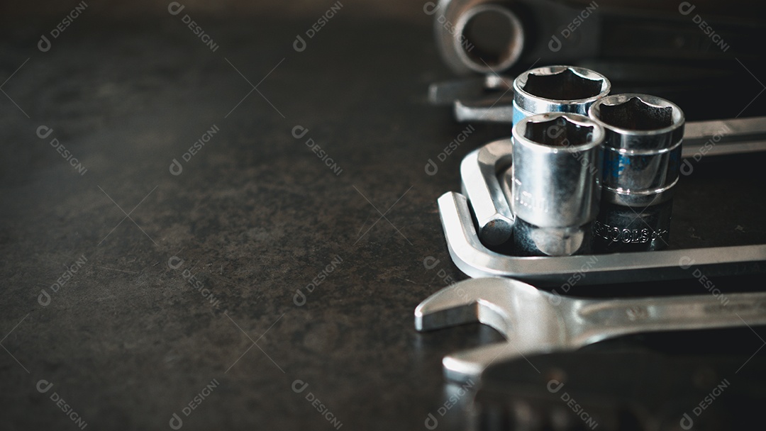 Ferramentas manuais consistindo de chaves, alicates, chaves de soquete, dispostas em fundo de chapa de aço antigo.