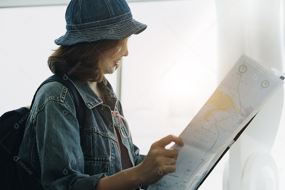 Mulher turista jovem viajante cobrindo com mapa de papel, rota de busca, no aeroporto internacional.