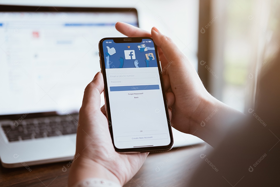 Mulher segurando um iPhone X com serviço social de Internet Facebook na tela.