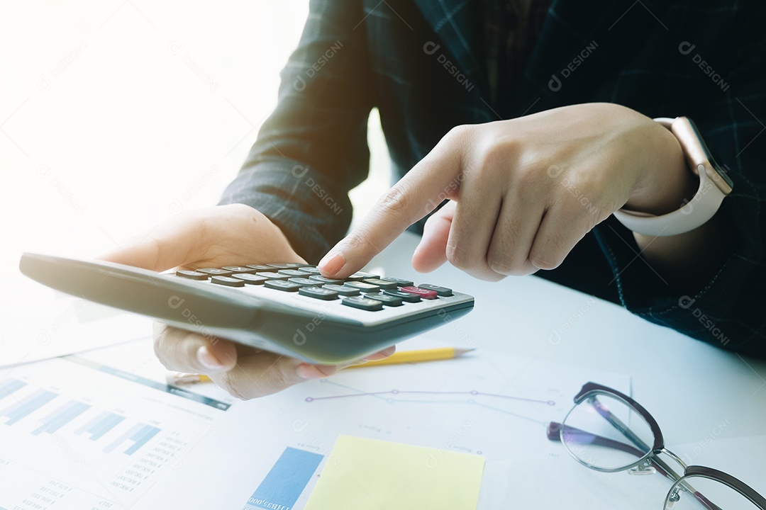 Mulher de negócios usando a calculadora para fazer finanças matemáticas na mesa de madeira no escritório e fundo de trabalho de negócios