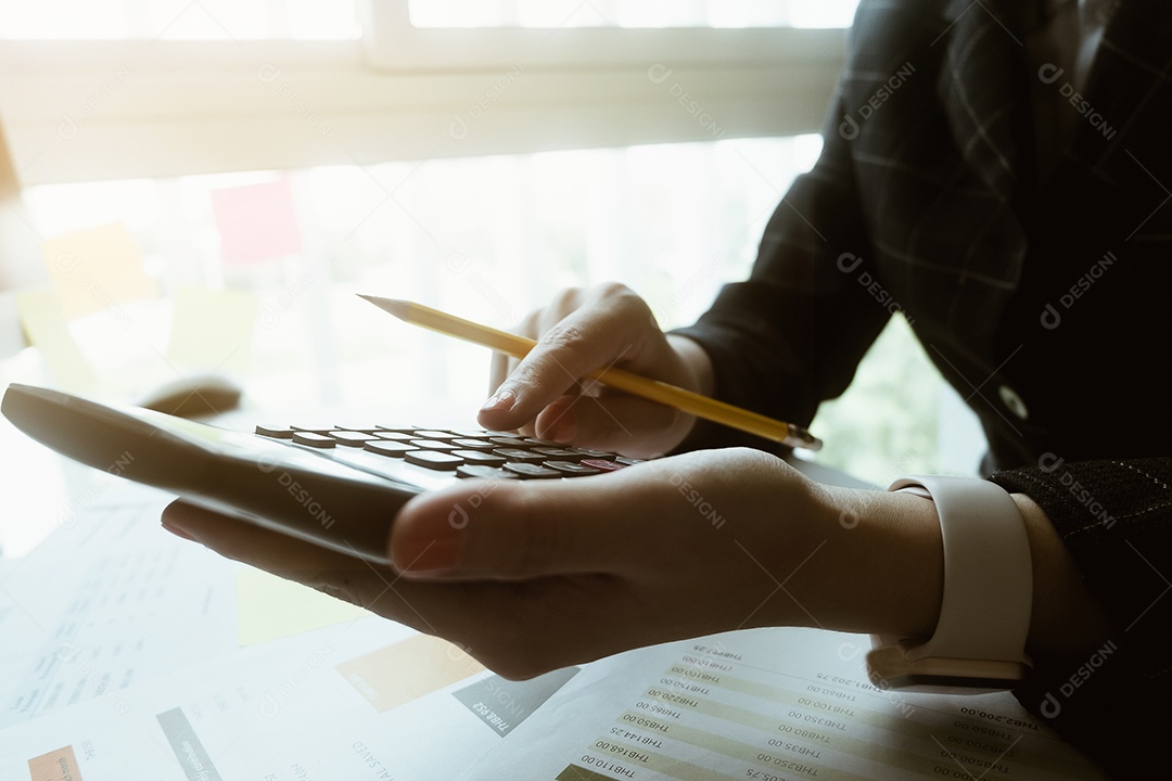 Mulher de negócios usando a calculadora para fazer finanças matemáticas na mesa de madeira no escritório e fundo de trabalho de negócios