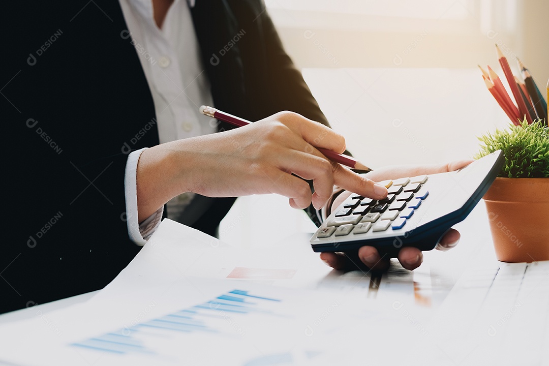 Mulher de negócios usando a calculadora para fazer finanças matemáticas na mesa de madeira no escritório e fundo de trabalho de negócios