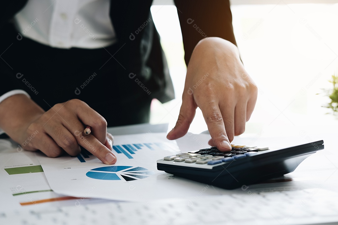 Mulher de negócios usando a calculadora para fazer finanças matemáticas na mesa de madeira no escritório e fundo de trabalho de negócios