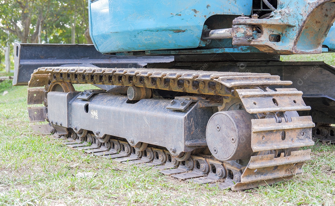 Feche a esteira rolante da retroescavadeira em vista lateral no gramado
