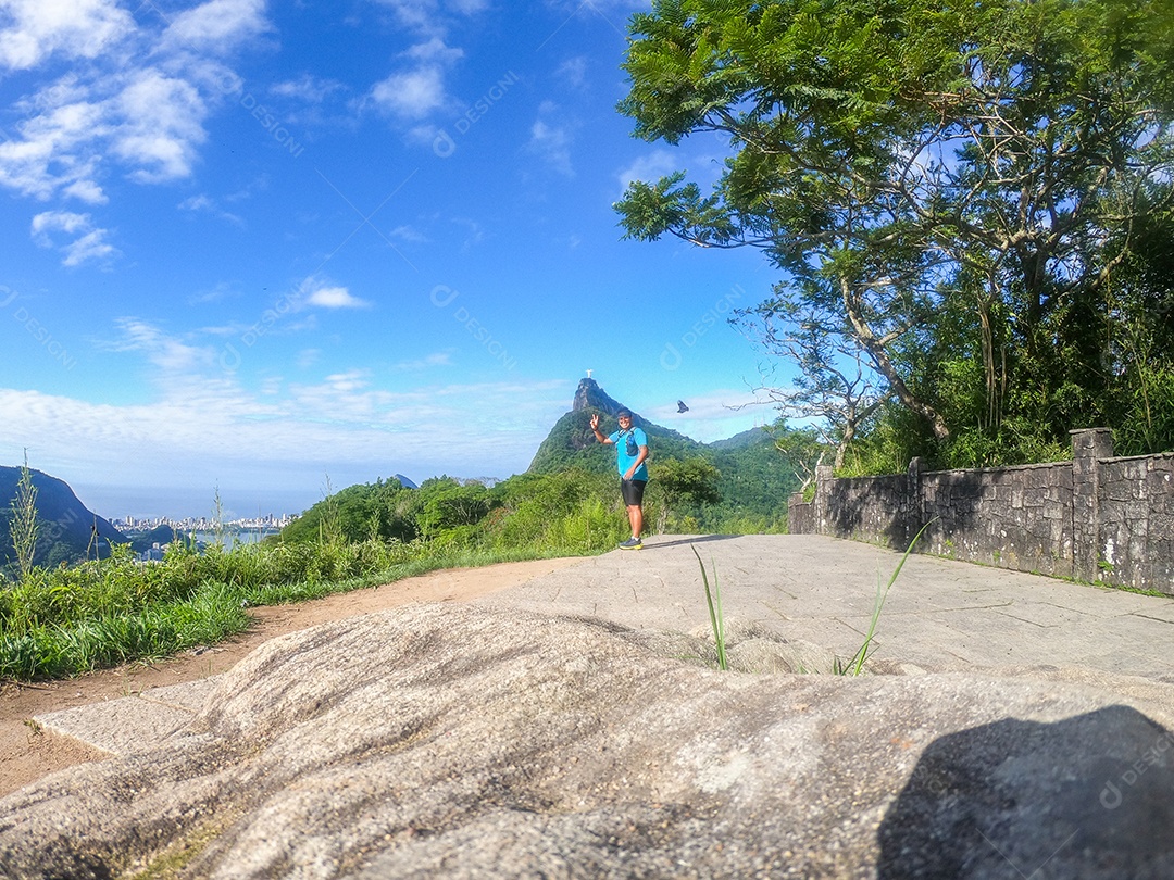 homem praticando corrida de rua no mirante dona marta com cristo redentor ao fundo no rio de janeiro, brasil.