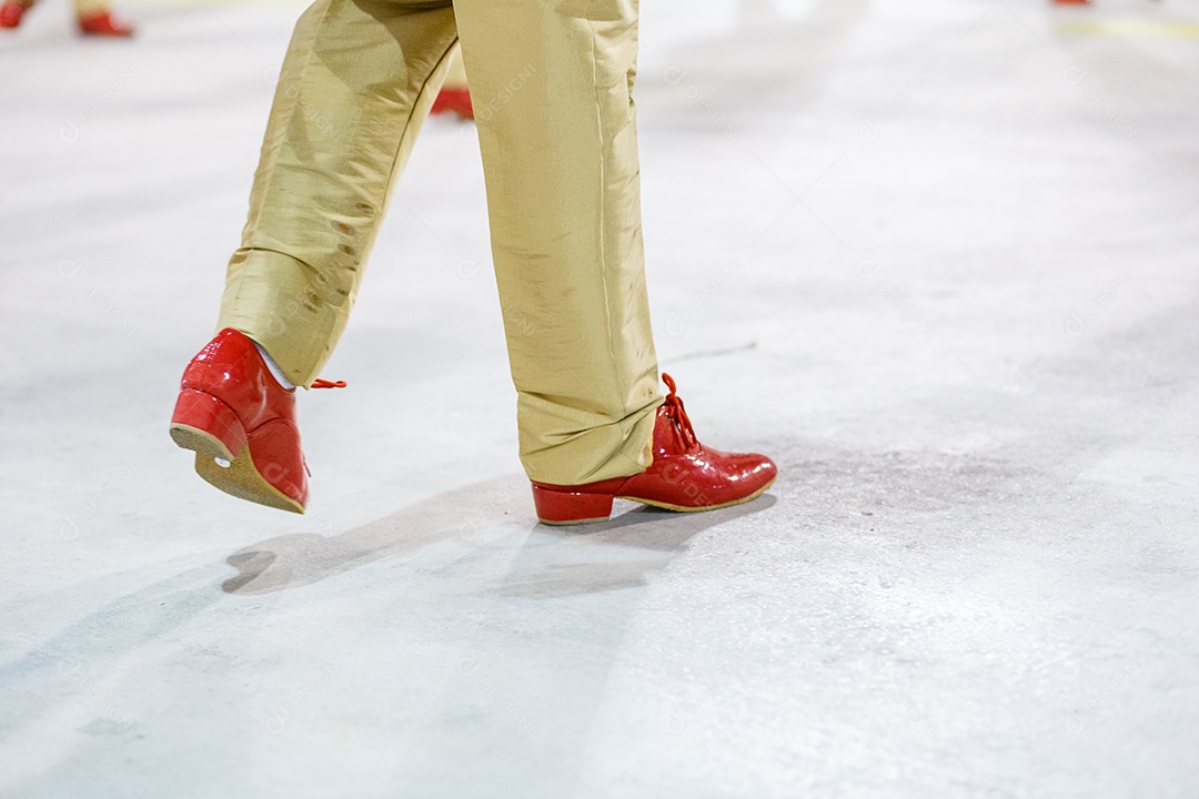 Sambista com calças cor de areia e sapatos vermelhos se apresentando no Rio de Janeiro, Brasil.