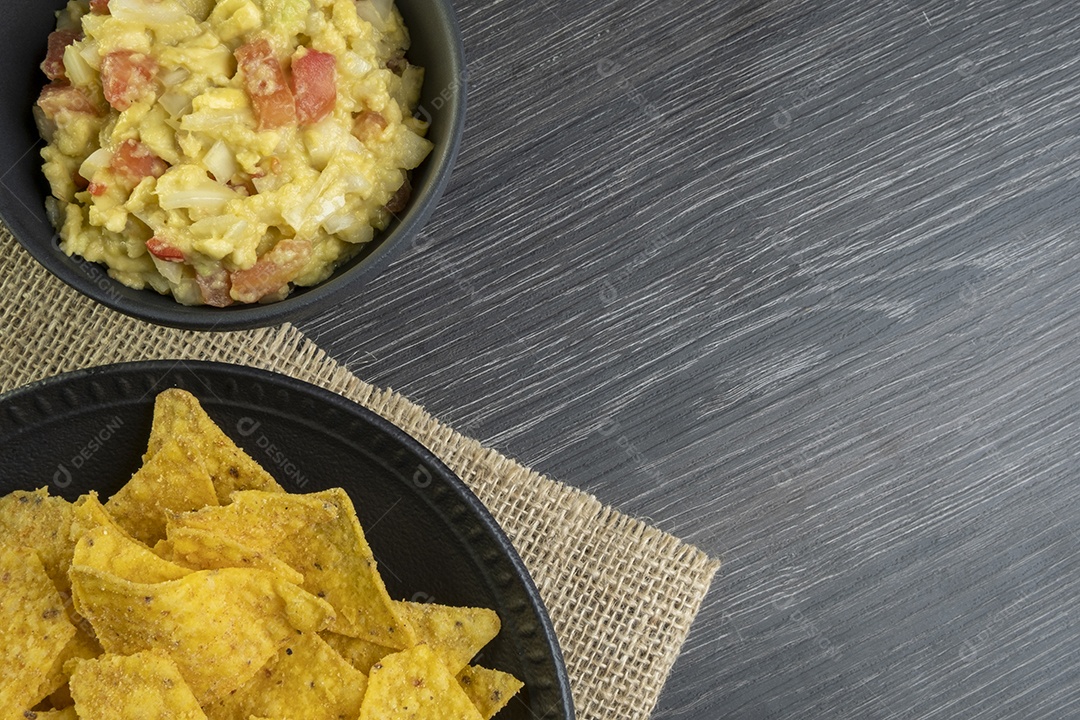 Guacamole com tortillas na mesa de madeira escura