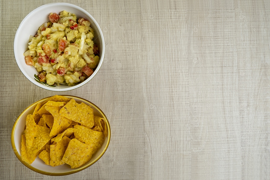 Guacamole com tortilhas na mesa de madeira