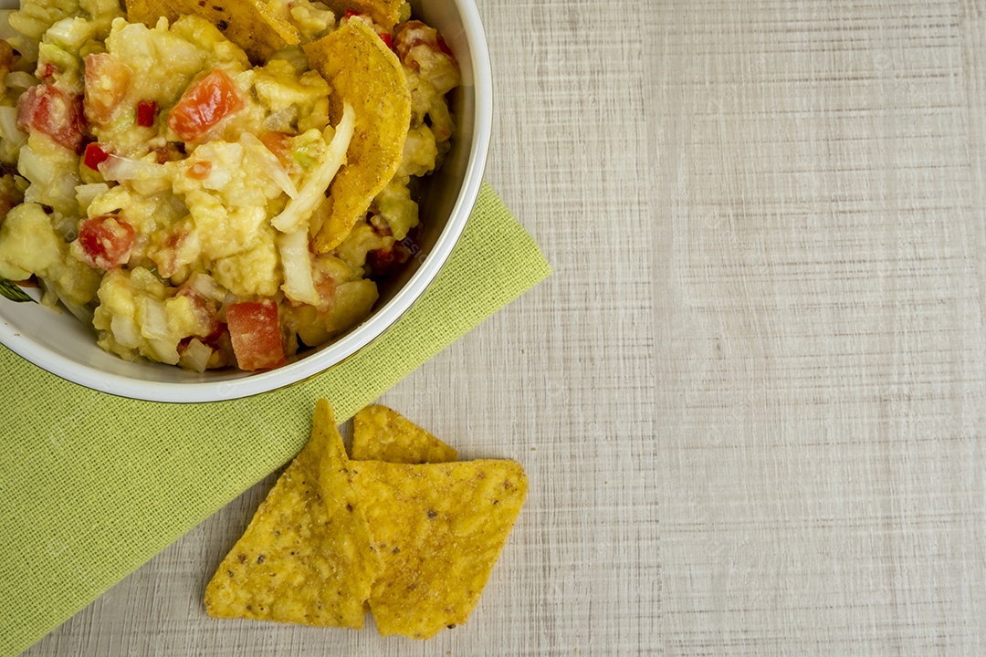 Guacamole com tortilhas na mesa de madeira