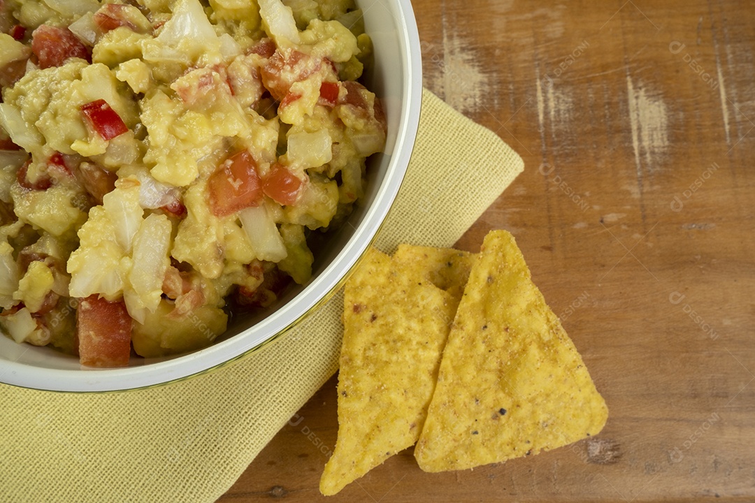 Guacamole com tortilhas na mesa de madeira