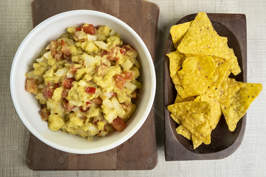 Tigelas com guacamole e tortillas na mesa de madeira