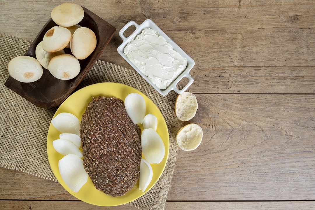 Quibe cru com cebola fatiada, requeijão, pão pita e folhas de hortelã.