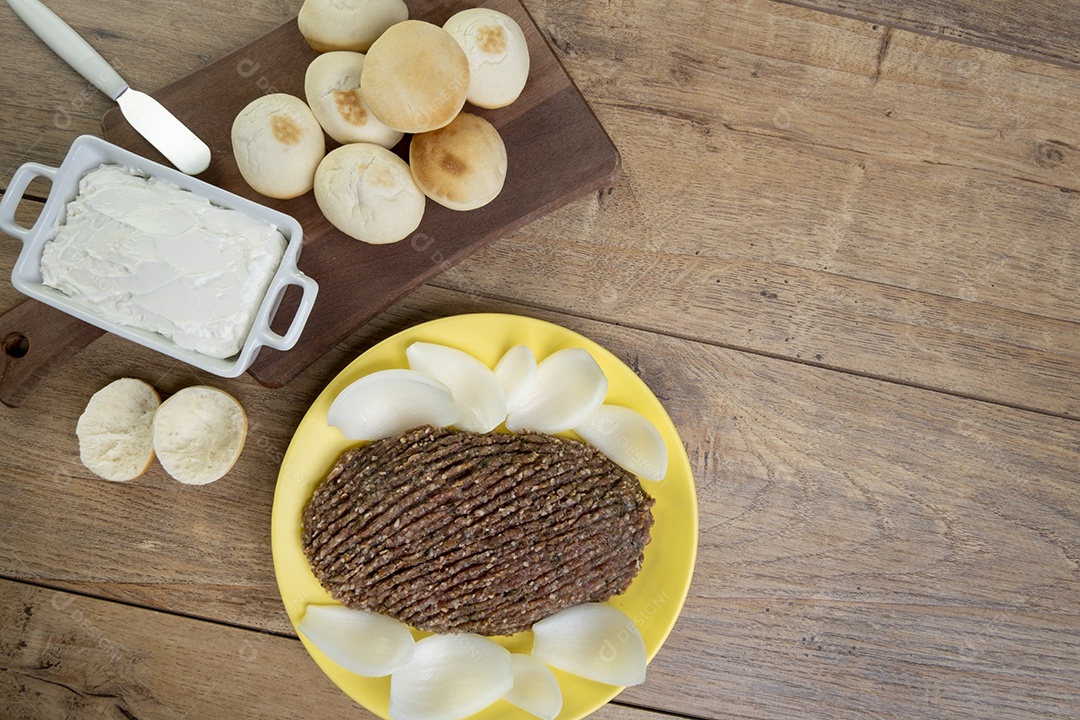 Quibe cru com cebola fatiada, requeijão, pão pita e folhas de hortelã.