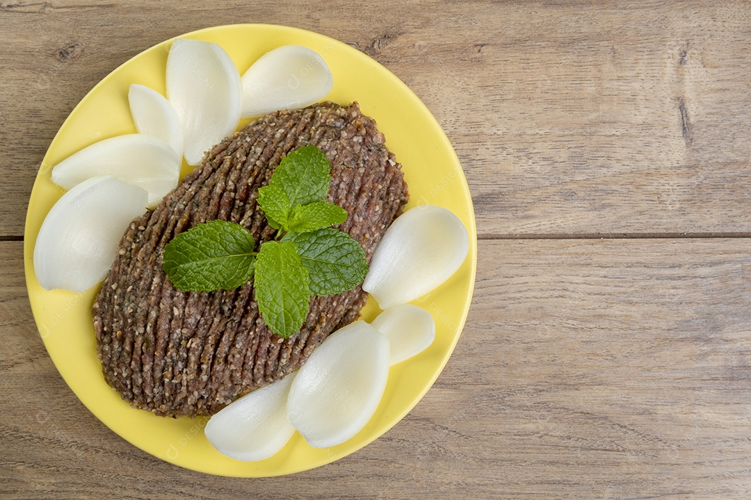 Quibe cru com cebola fatiada e um raminho de hortelã