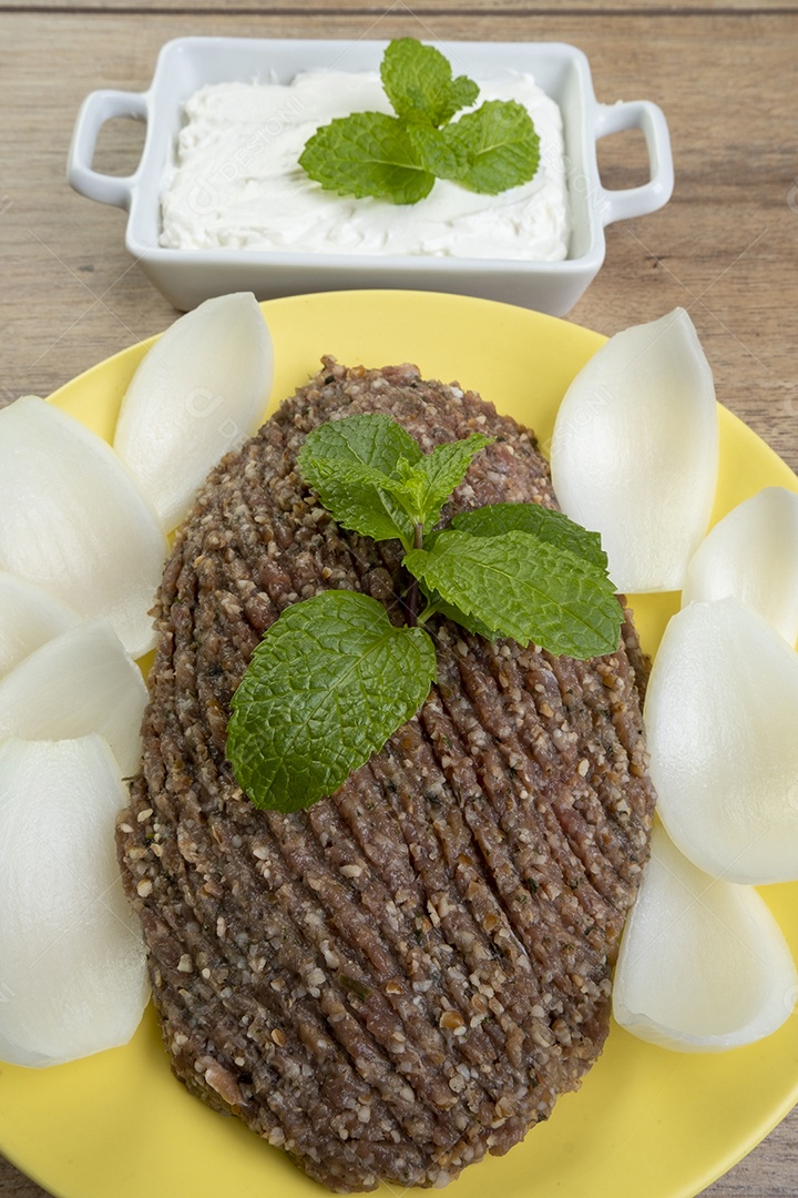 Quibe cru com cebola fatiada, requeijão, pão pita e folhas de hortelã.