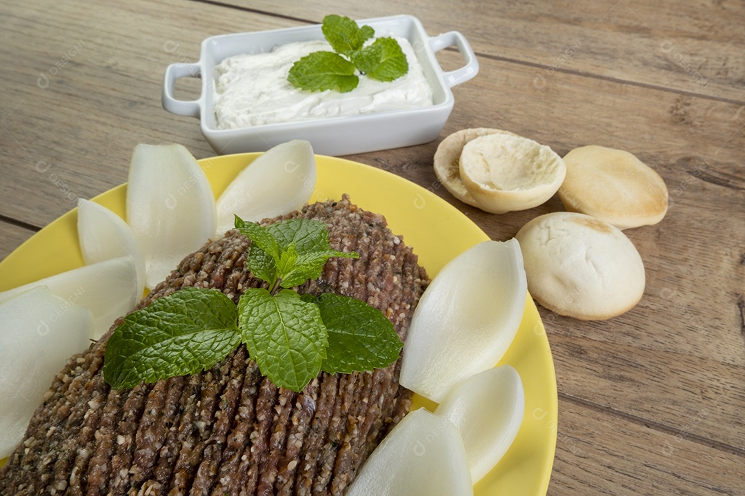 Quibe cru com cebola fatiada, requeijão, pão pita e folhas de hortelã.