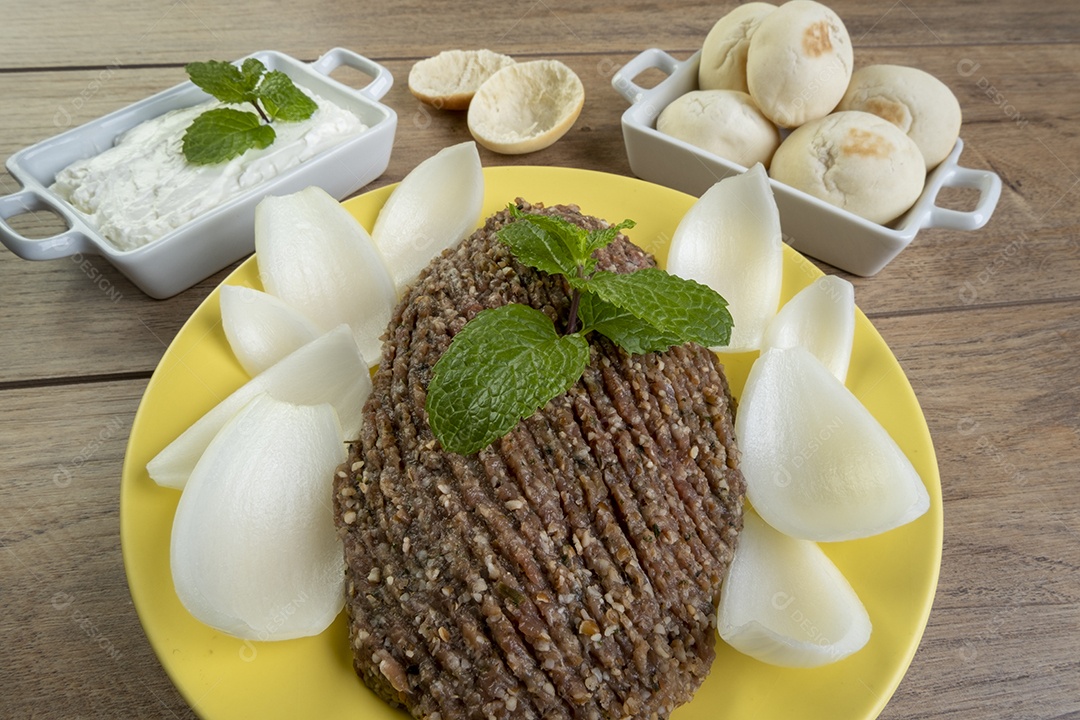 Quibe cru com cebola fatiada, requeijão, pão pita e folhas de hortelã.