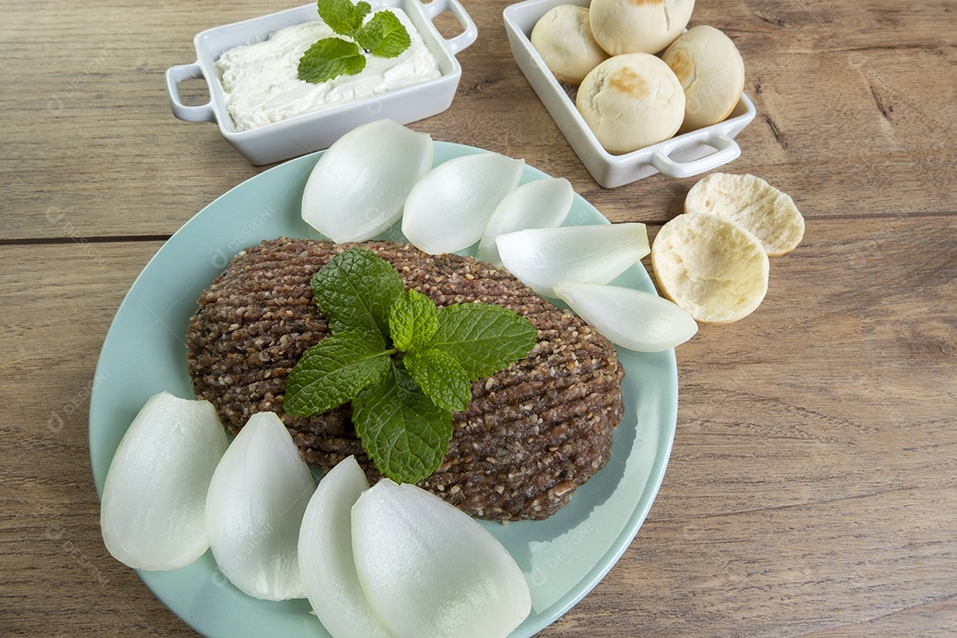 Quibe cru com cebola fatiada, requeijão, pão pita e folhas de hortelã.