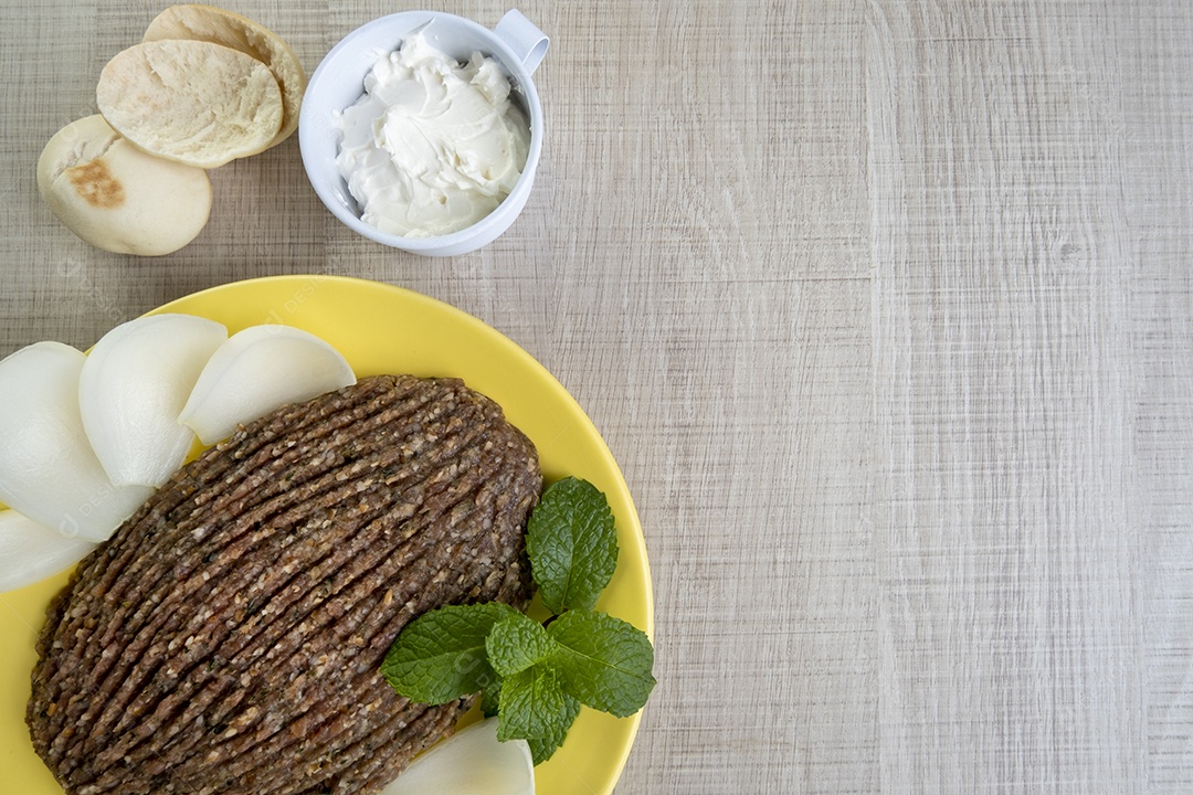 Quibe cru com cebola fatiada, requeijão seco, pão sírio e folha de hortelã