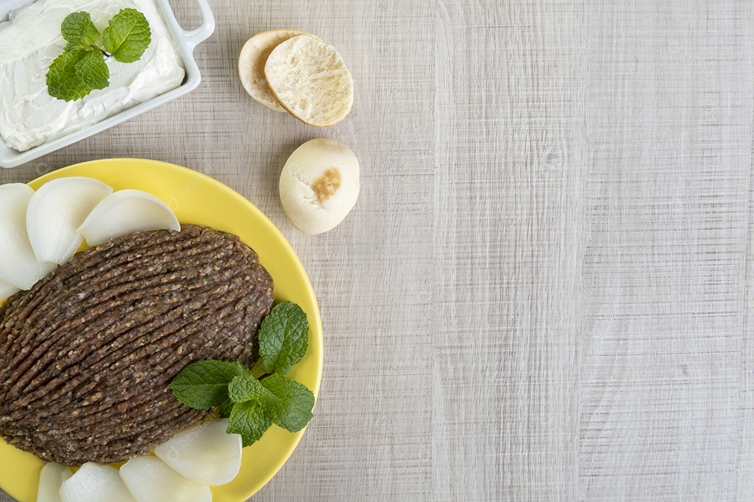 Quibe cru com cebola fatiada, requeijão seco, pão sírio e folha de hortelã