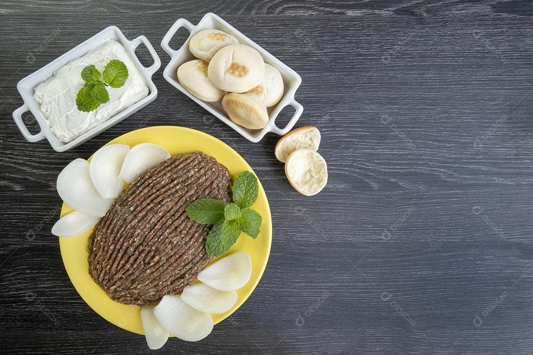 Quibe cru com cebola fatiada, requeijão seco, pão sírio e folha de hortelã