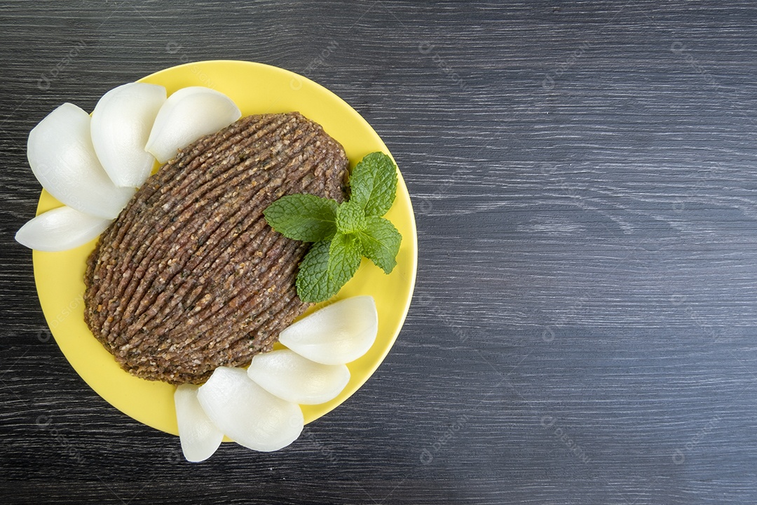 Quibe cru com cebola fatiada e um raminho de hortelã
