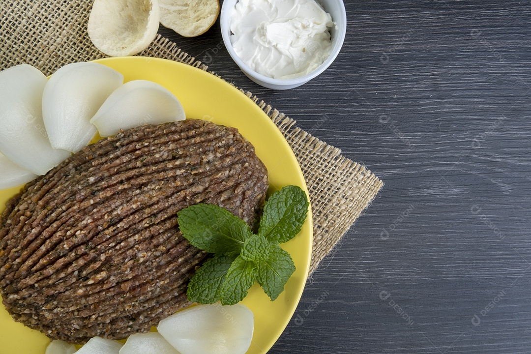 Quibe cru com cebola fatiada, requeijão, pão pita e folhas de hortelã.