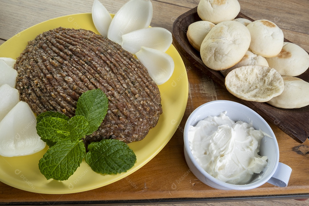 Quibe cru com cebola fatiada, requeijão, pão pita e folhas de hortelã.