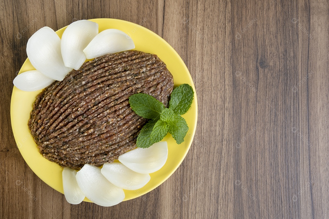 Quibe cru com cebola fatiada e um raminho de hortelã