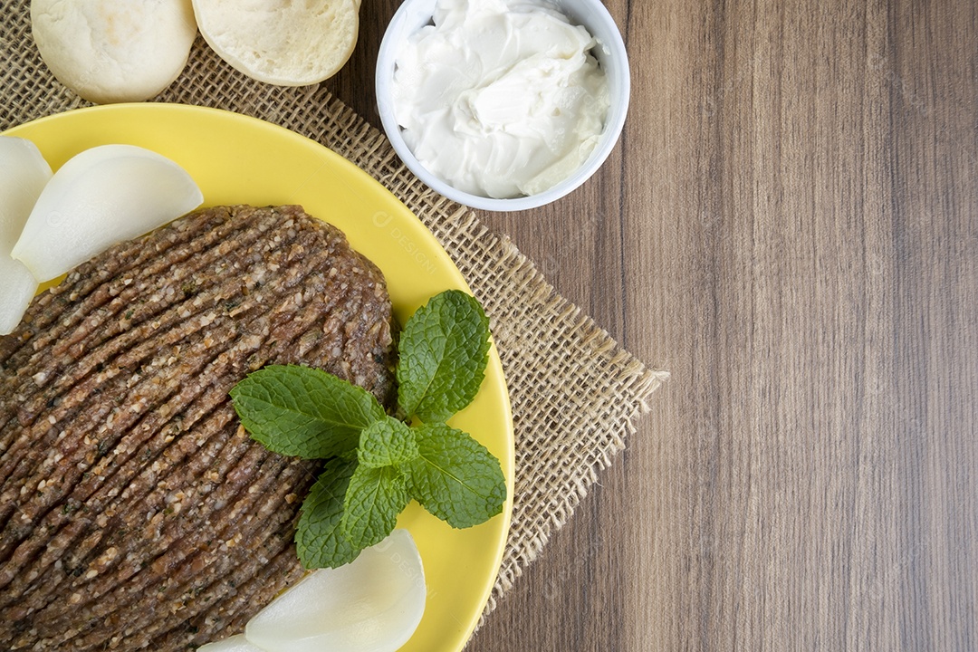 Quibe cru com cebola fatiada, requeijão, pão pita e folhas de hortelã.