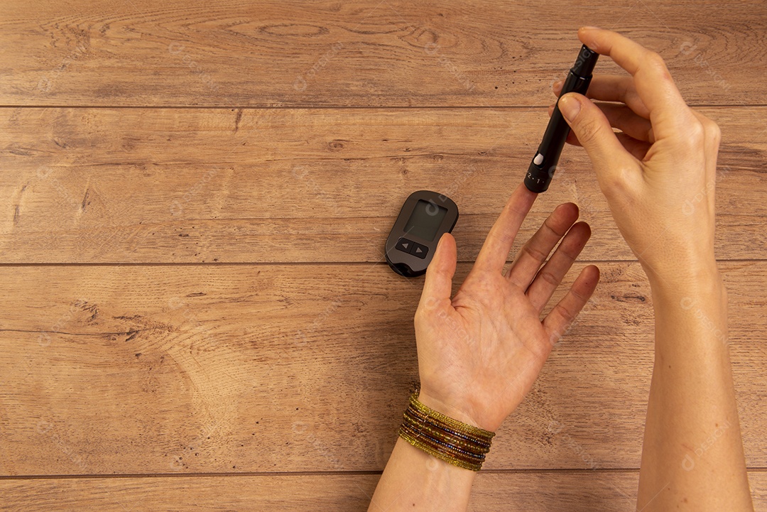 Mãos de mulher diabética usando dispositivos para medir a glicose no sangue