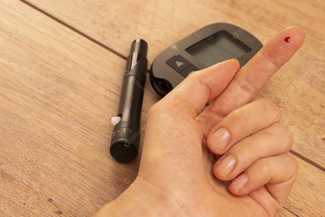 Uma gota de sangue no dedo de uma mulher para medir a glicose usando glicosímetro.