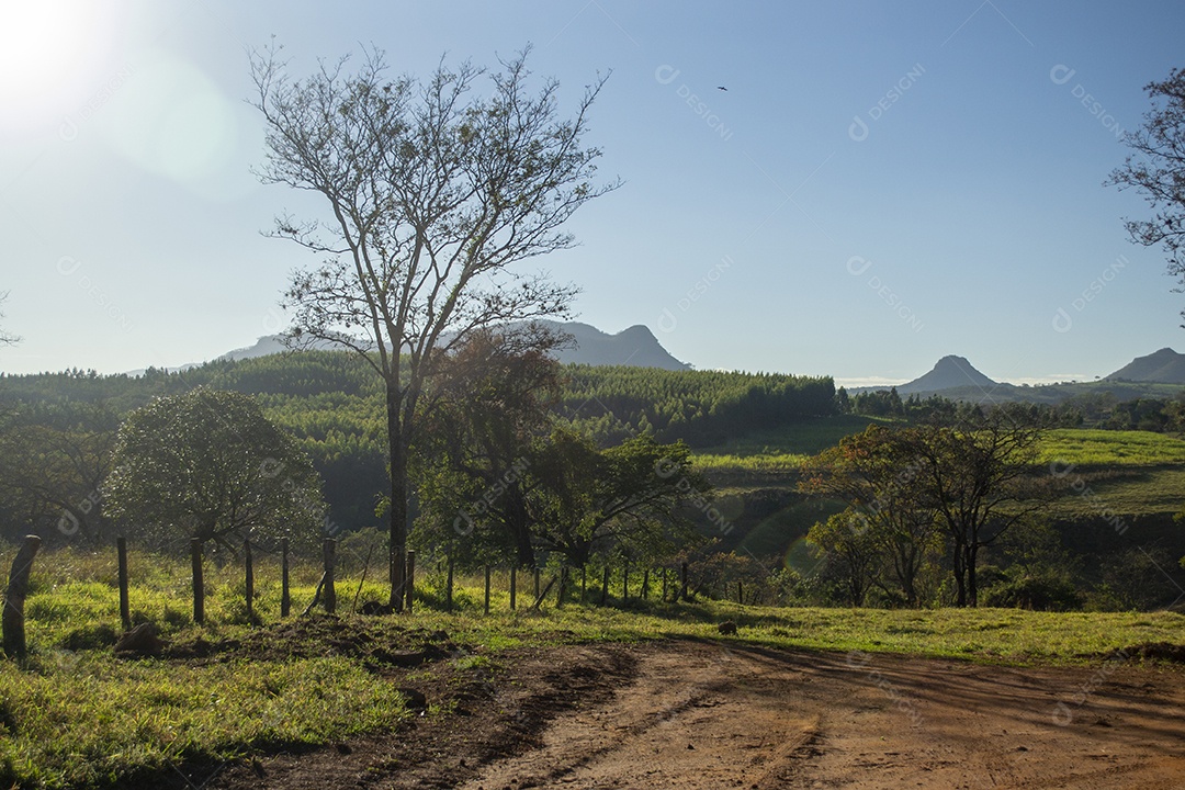 Área rural ao sol do amanhecer com pequenas montanhas ao fundo