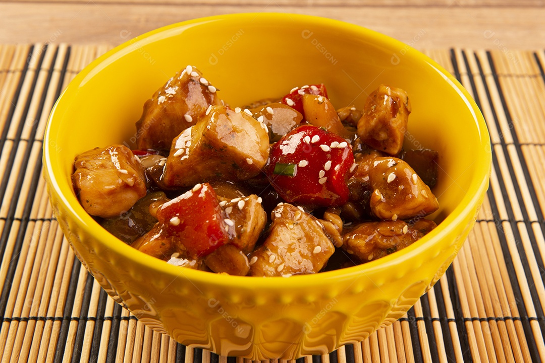 Frango xadrez em tigela amarela sobre fundo de madeira - comida chinesa