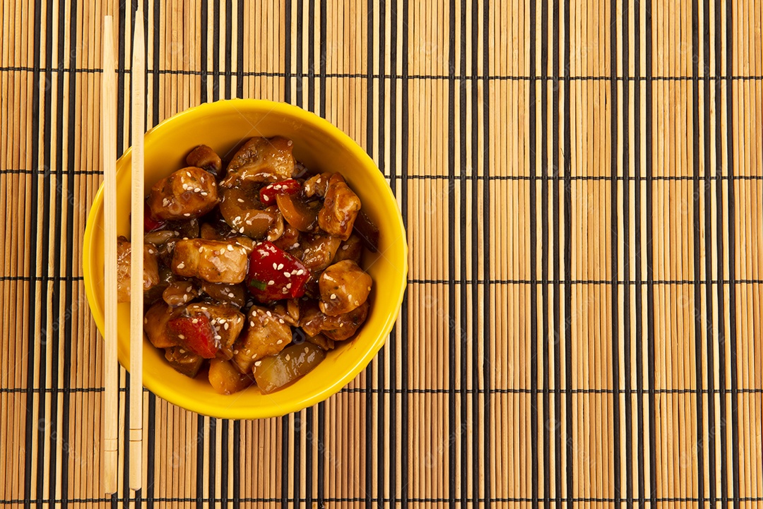 Frango xadrez em tigela amarela sobre fundo de madeira - comida chinesa