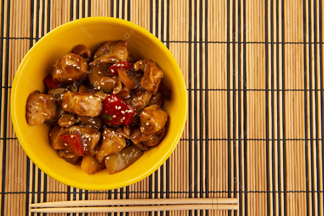 Frango xadrez em tigela amarela sobre fundo de madeira - comida chinesa